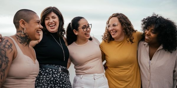 Five women sharing a joyful moment together outdoors
